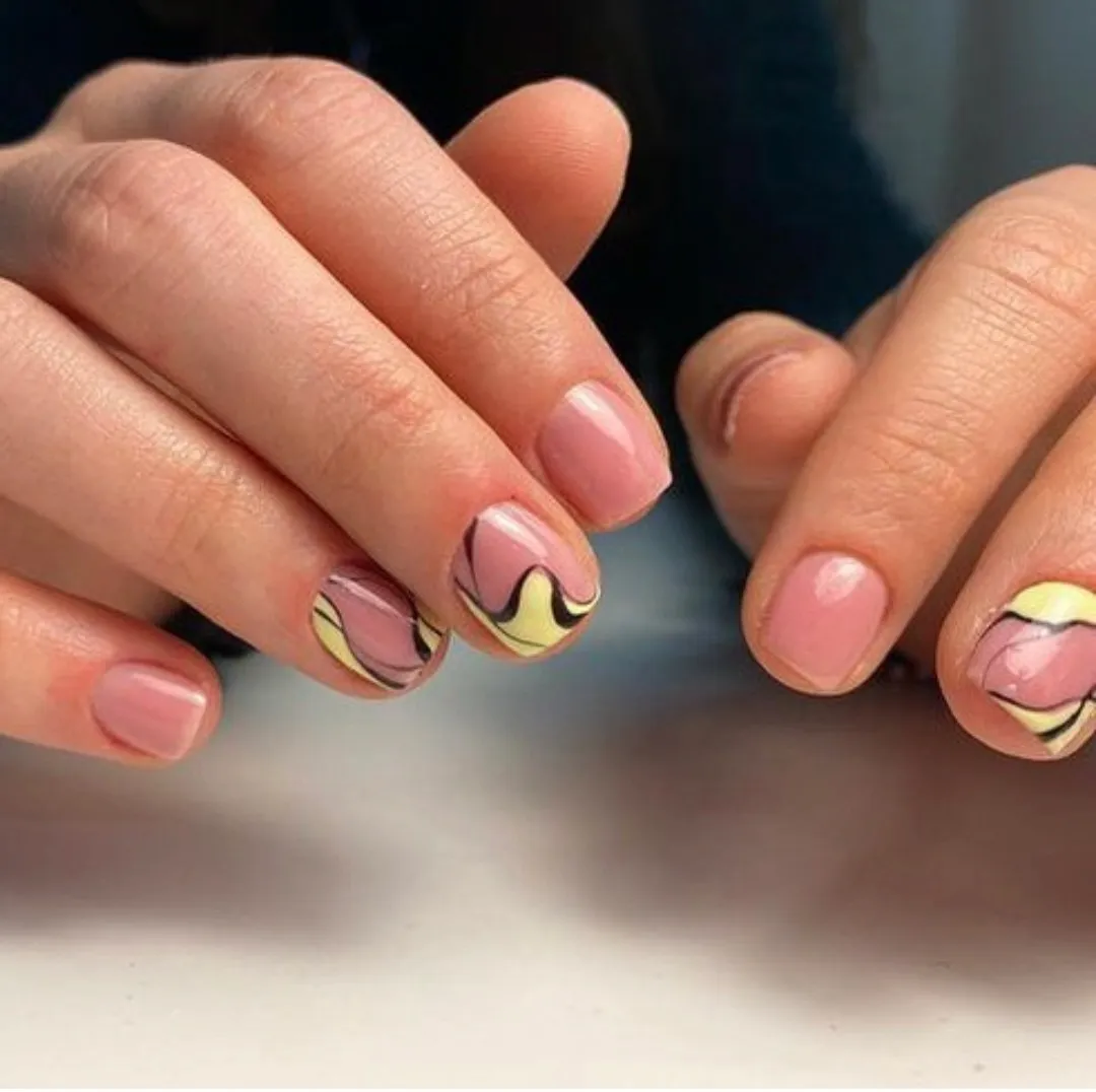 Short pink nails with abstract yellow and black swirls